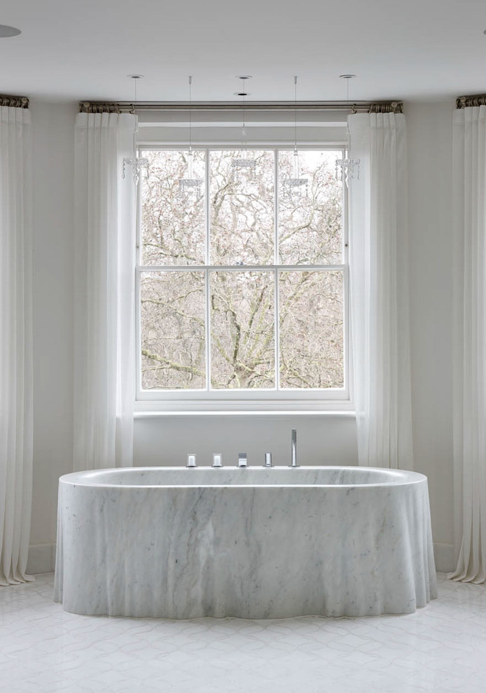 Photo of a transitional master bathroom in London with a freestanding tub and white walls.