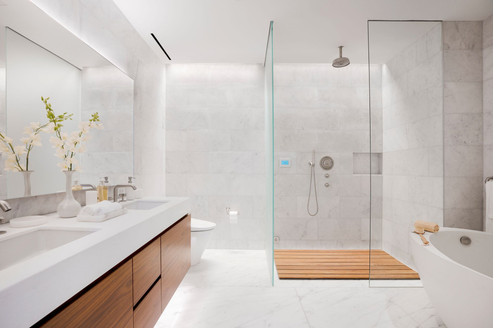 Mid-sized contemporary master bathroom in New York with flat-panel cabinets, medium wood cabinets, a freestanding tub, a curbless shower, marble, marble floors, an undermount sink, multi-coloured floor, an open shower and white benchtops.