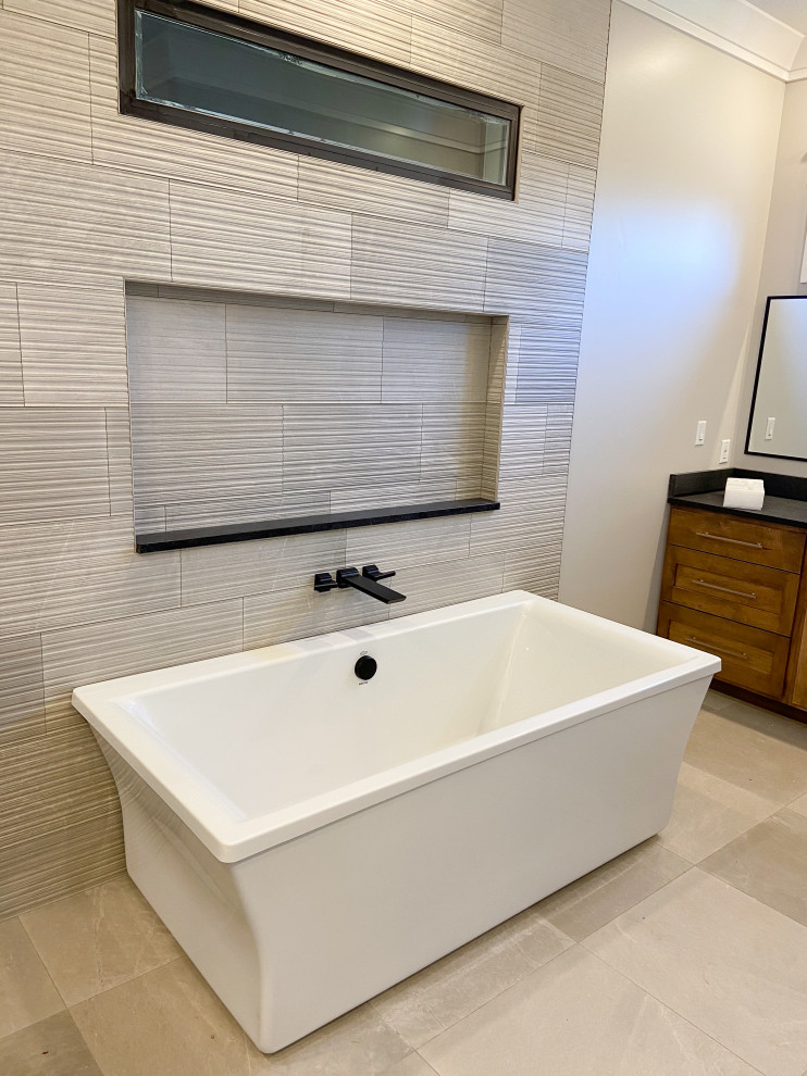 Example of a large gray tile and porcelain tile porcelain tile and gray floor freestanding bathtub design with gray walls, granite countertops and black countertops