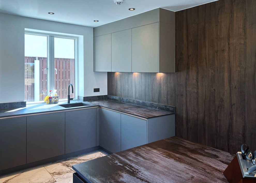 Inspiration for a mid-sized modern u-shaped open plan kitchen in London with flat-panel cabinets, grey cabinets, black appliances, with island and brown benchtop.