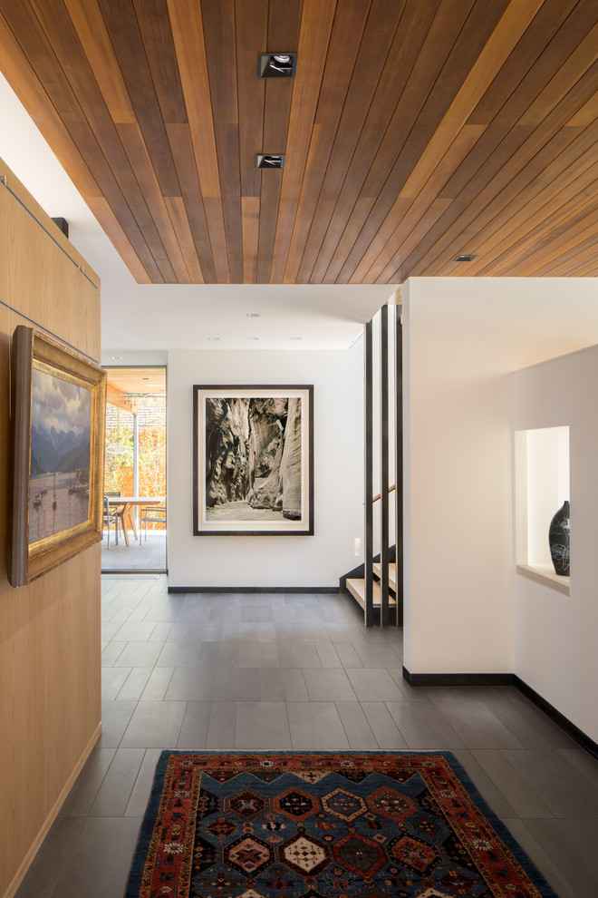 Photo of a modern foyer in Denver with white walls, ceramic floors, a single front door and a medium wood front door.
