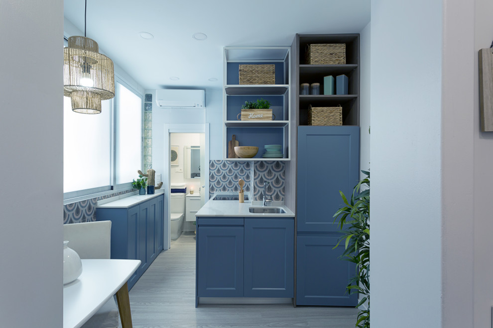 This is an example of a small modern l-shaped kitchen/diner in Madrid with a submerged sink, open cabinets, blue cabinets, marble worktops, blue splashback, ceramic splashback, integrated appliances, light hardwood flooring, grey floors and white worktops.