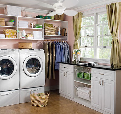 Large traditional l-shaped utility room in San Diego with raised-panel cabinets, white cabinets, pink walls, light hardwood floors and a side-by-side washer and dryer.