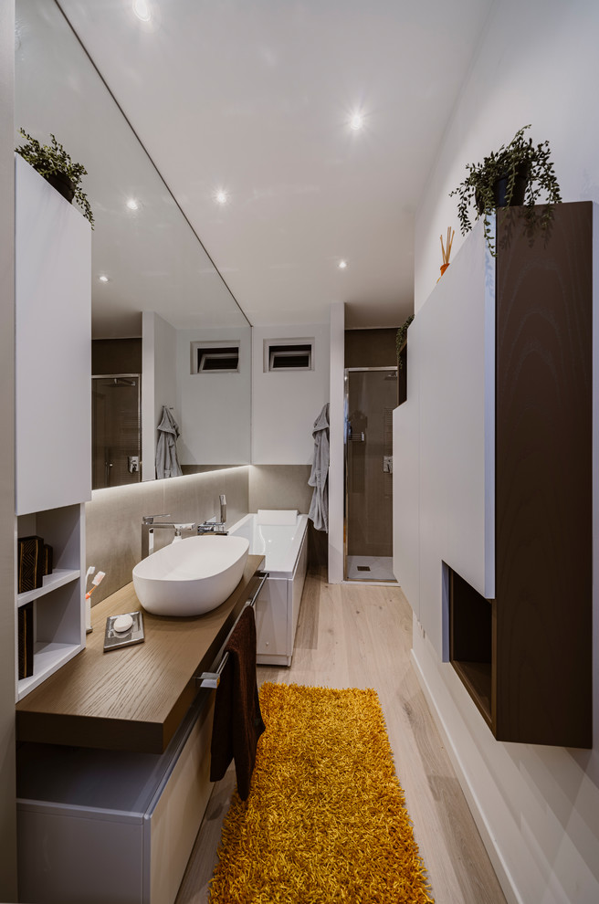 Small modern 3/4 bathroom in Milan with flat-panel cabinets, beige cabinets, a corner tub, an alcove shower, a two-piece toilet, beige tile, porcelain tile, beige walls, light hardwood floors, a vessel sink, wood benchtops, beige floor, a sliding shower screen and brown benchtops.