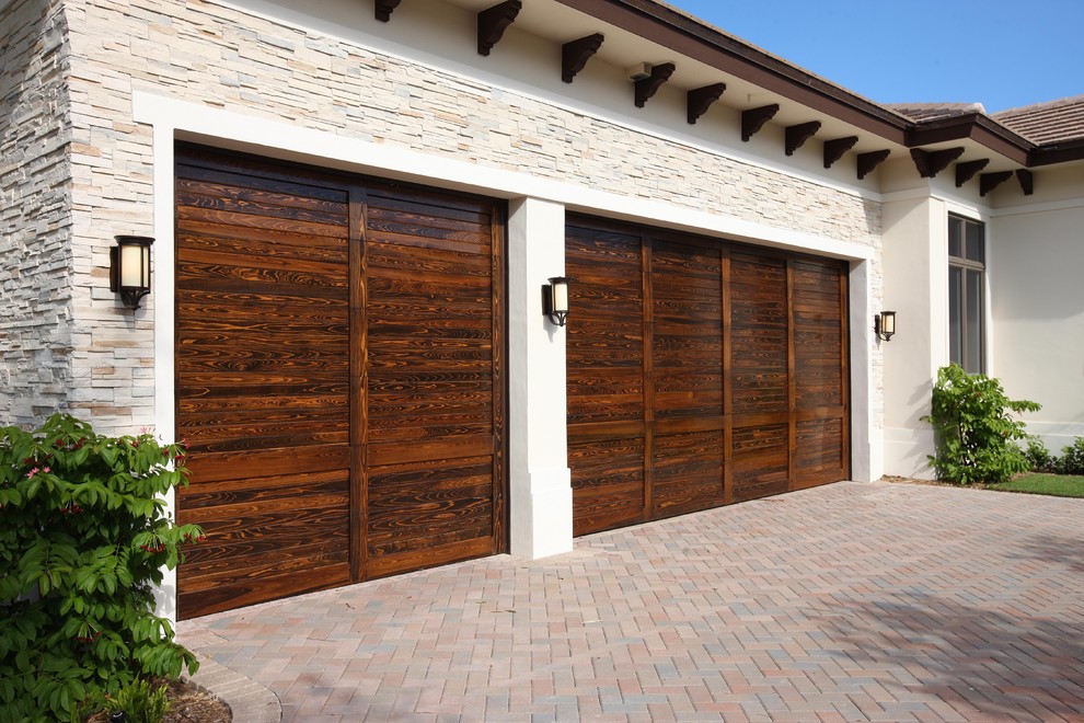 This is an example of a large contemporary attached three-car garage in Miami.
