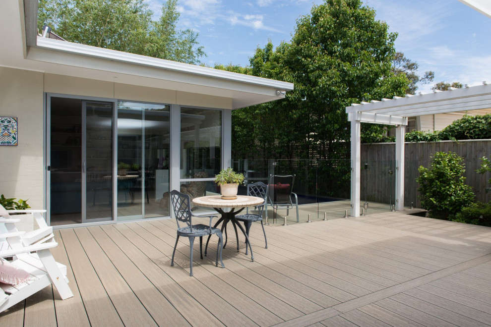 Design ideas for a large beach style backyard and ground level deck in Melbourne with no cover and glass railing.