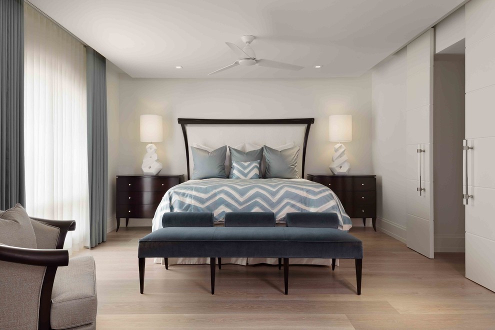 This is an example of a large contemporary guest bedroom in Miami with white walls and light hardwood floors.