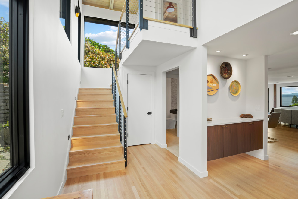 This is an example of a midcentury wood u-shaped staircase in Seattle with wood risers and cable railing.