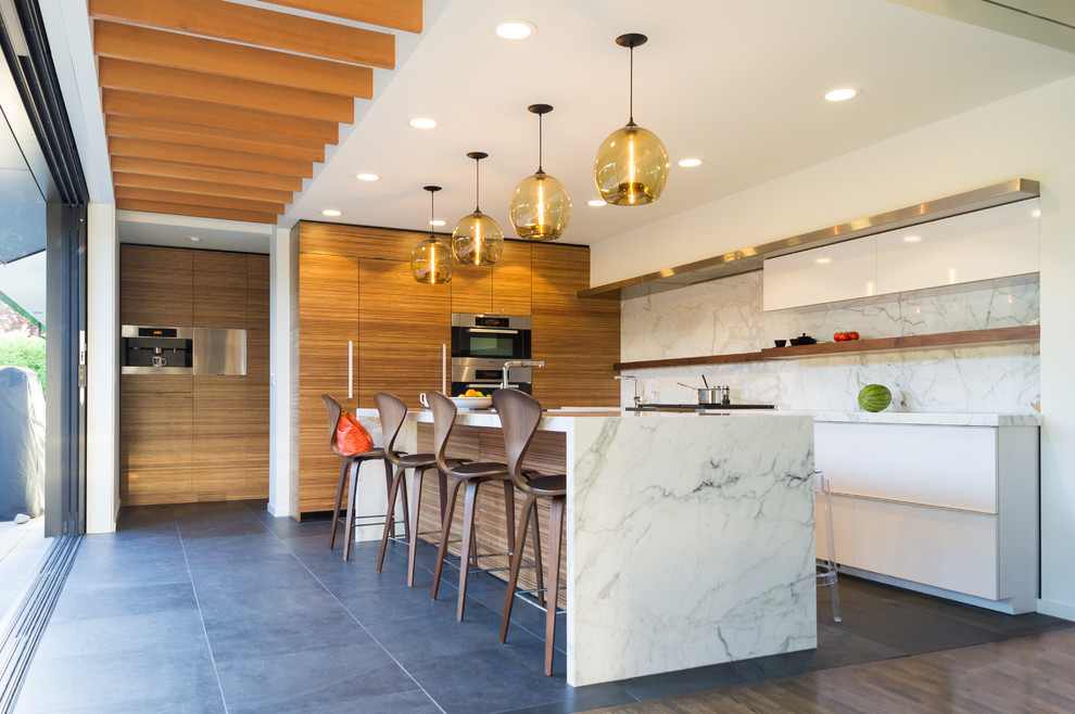 Contemporary galley eat-in kitchen in Seattle with an undermount sink, flat-panel cabinets, white cabinets, marble benchtops, white splashback, stone slab splashback and stainless steel appliances.