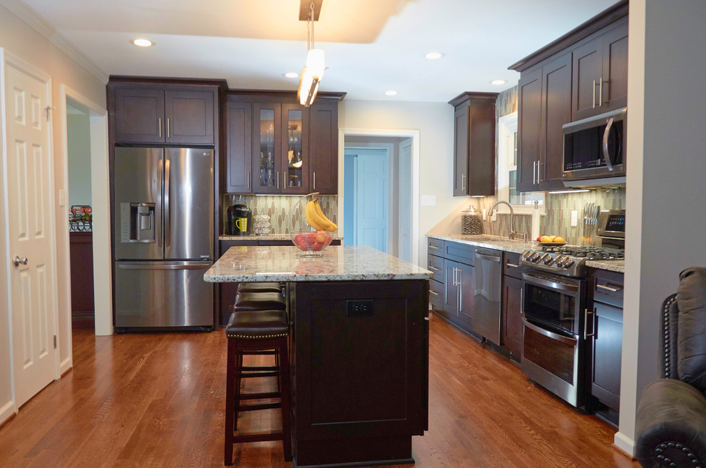 Open concept kitchen - transitional l-shaped medium tone wood floor and brown floor open concept kitchen idea with an undermount sink, shaker cabinets, dark wood cabinets, granite countertops, multicolored backsplash, mosaic tile backsplash, stainless steel appliances, an island and white countertops