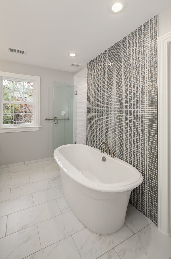 This is an example of a large transitional master bathroom in DC Metro with shaker cabinets, white cabinets, a freestanding tub, an alcove shower, brown tile, glass tile, grey walls, marble floors, an undermount sink and marble benchtops.