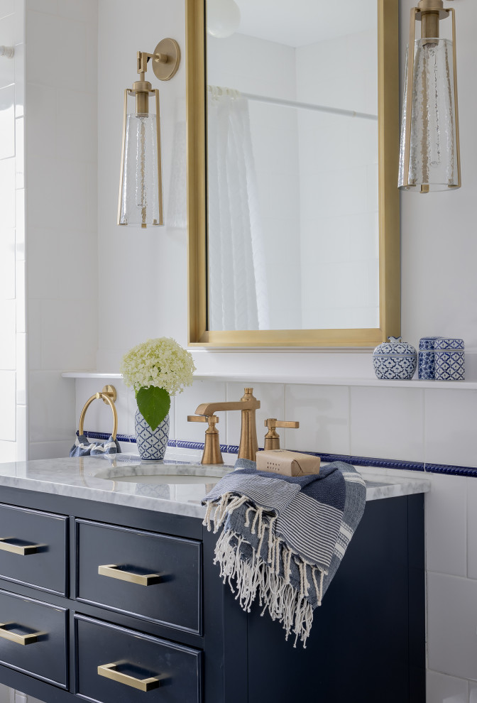 This is an example of a mid-sized traditional powder room in Boston with blue cabinets, a one-piece toilet, white tile, cement tile, white walls, ceramic floors, an undermount sink, marble benchtops, white floor, blue benchtops and a freestanding vanity.