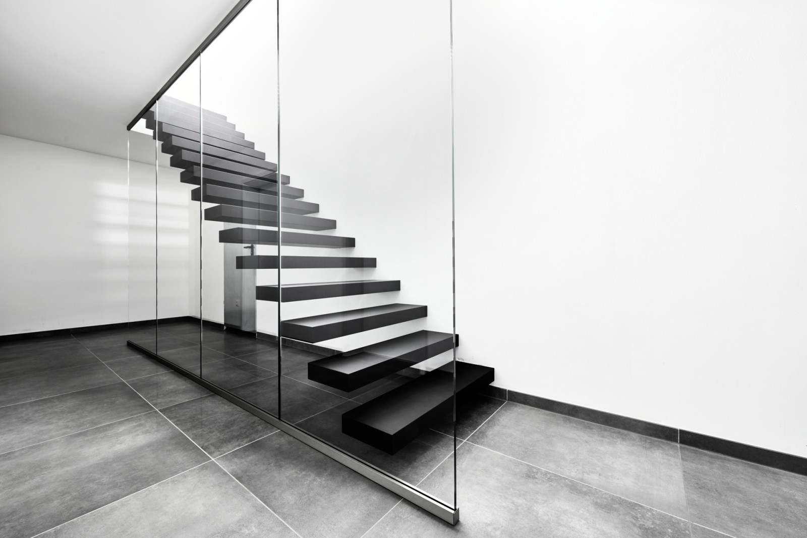 Консольная лестница в черном матовом цвете с ограждением из белого стекла