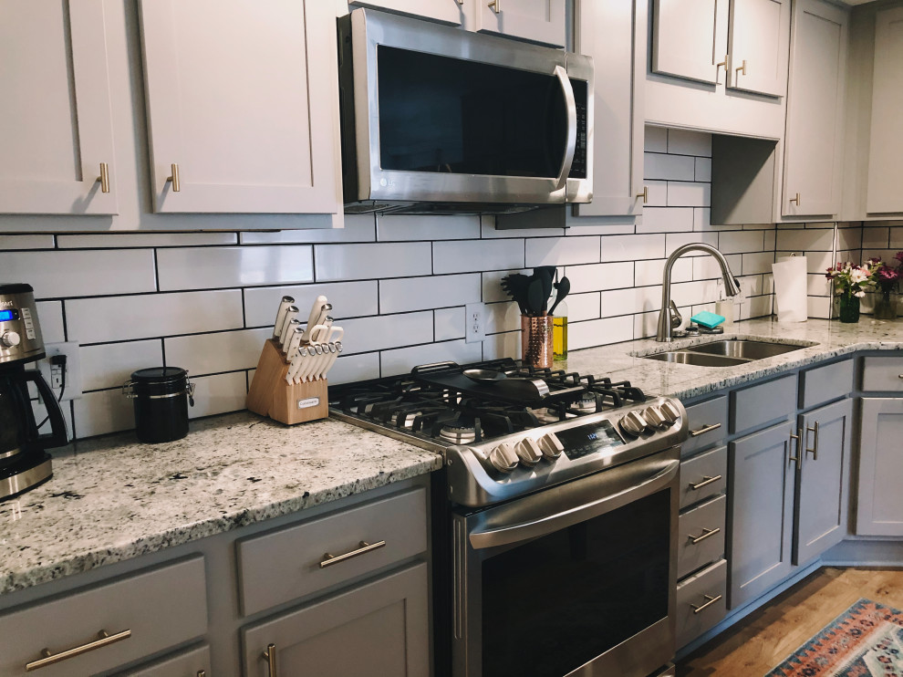 Inspiration for a mid-sized country l-shaped eat-in kitchen in Indianapolis with an undermount sink, shaker cabinets, grey cabinets, granite benchtops, white splashback, ceramic splashback, stainless steel appliances, vinyl floors, with island, brown floor and grey benchtop.