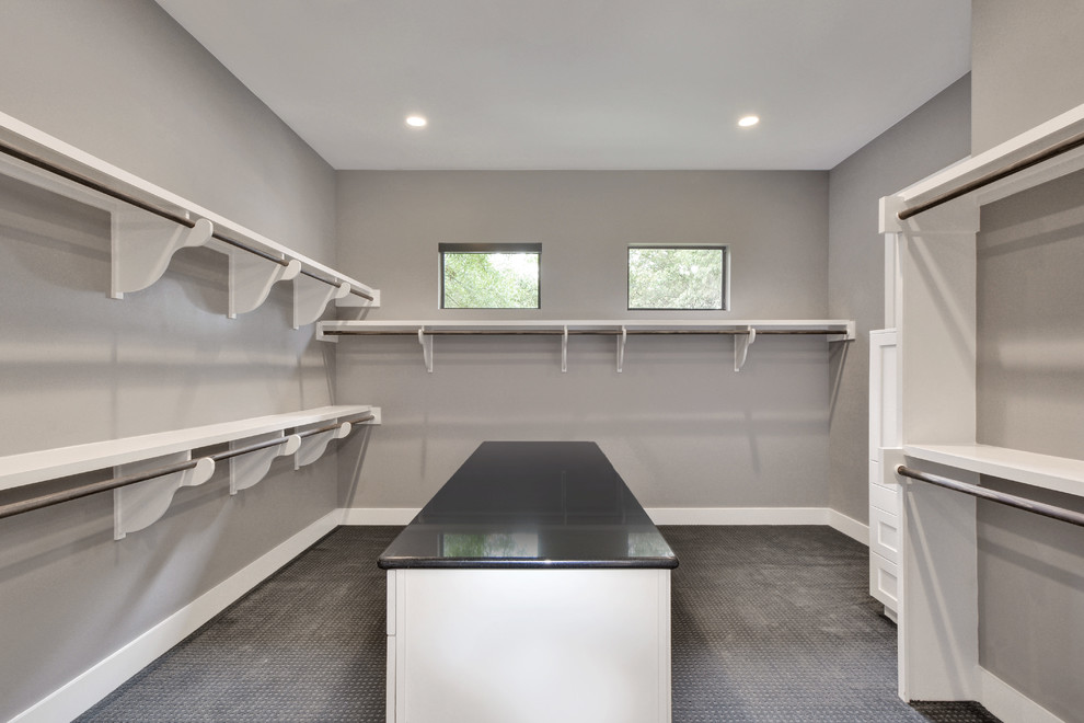 This is an example of a large modern gender-neutral walk-in wardrobe in Austin with shaker cabinets, white cabinets and carpet.