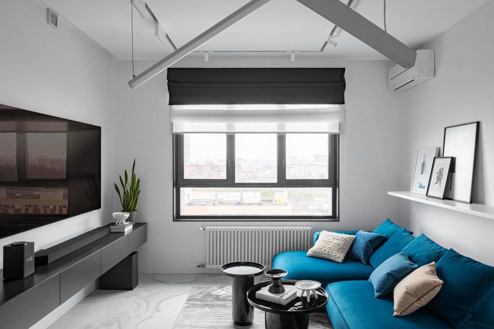 На фото: серо-белая гостиная комната среднего размера в современном стиле с белыми стенами, полом из керамогранита, телевизором на стене, серым полом и синим диваном без камина