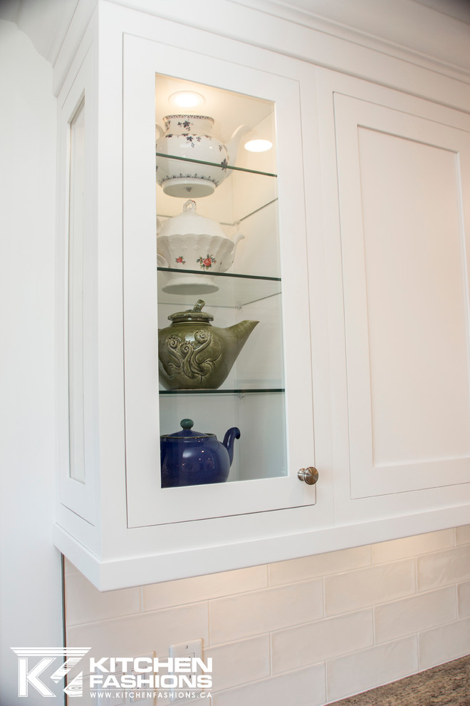 Inspiration for a large transitional u-shaped light wood floor eat-in kitchen remodel with a farmhouse sink, shaker cabinets, white cabinets, granite countertops, white backsplash, subway tile backsplash, stainless steel appliances and no island