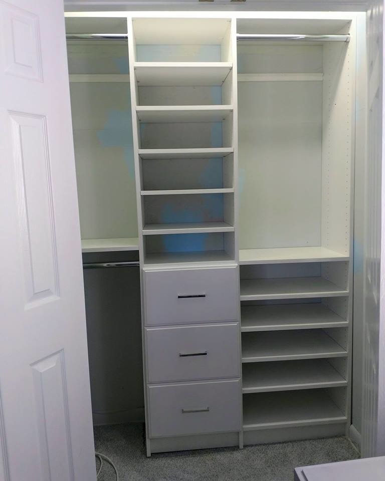 Design ideas for a mid-sized gender-neutral built-in wardrobe in New York with flat-panel cabinets, white cabinets, carpet and grey floor.
