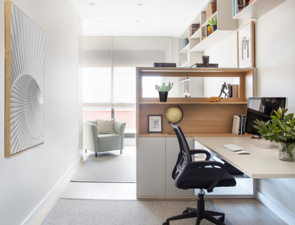 Стильный дизайн: рабочее место в современном стиле с белыми стенами, паркетным полом среднего тона и встроенным рабочим столом - последний тренд
