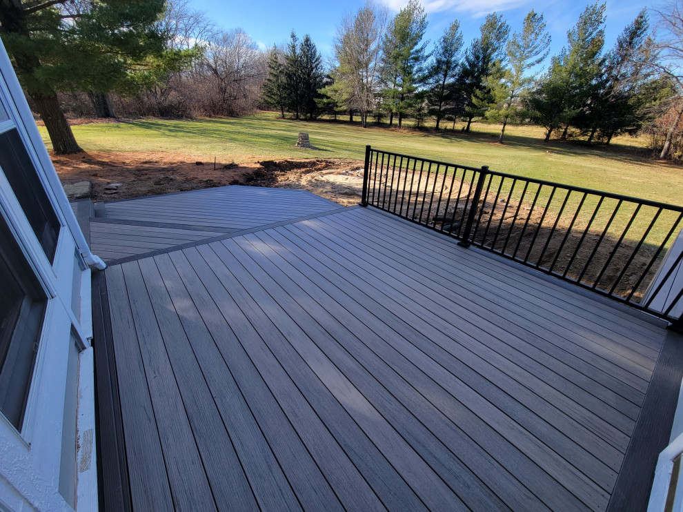Example of a mid-sized backyard ground level metal railing deck design with no cover
