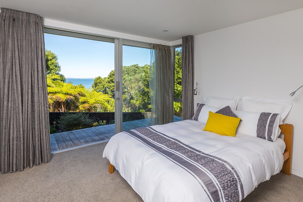 This is an example of a mid-sized contemporary master bedroom in Auckland with yellow walls and carpet.