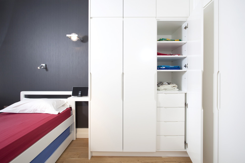 Photo of a contemporary gender-neutral kids' bedroom for kids 4-10 years old in London with grey walls and light hardwood floors.