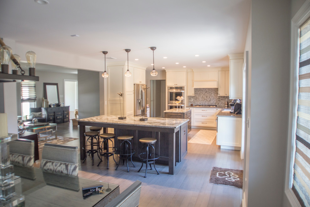 Eat-in kitchen - mid-sized transitional l-shaped dark wood floor eat-in kitchen idea in New York with an undermount sink, recessed-panel cabinets, beige cabinets, quartz countertops, multicolored backsplash, subway tile backsplash, stainless steel appliances and two islands