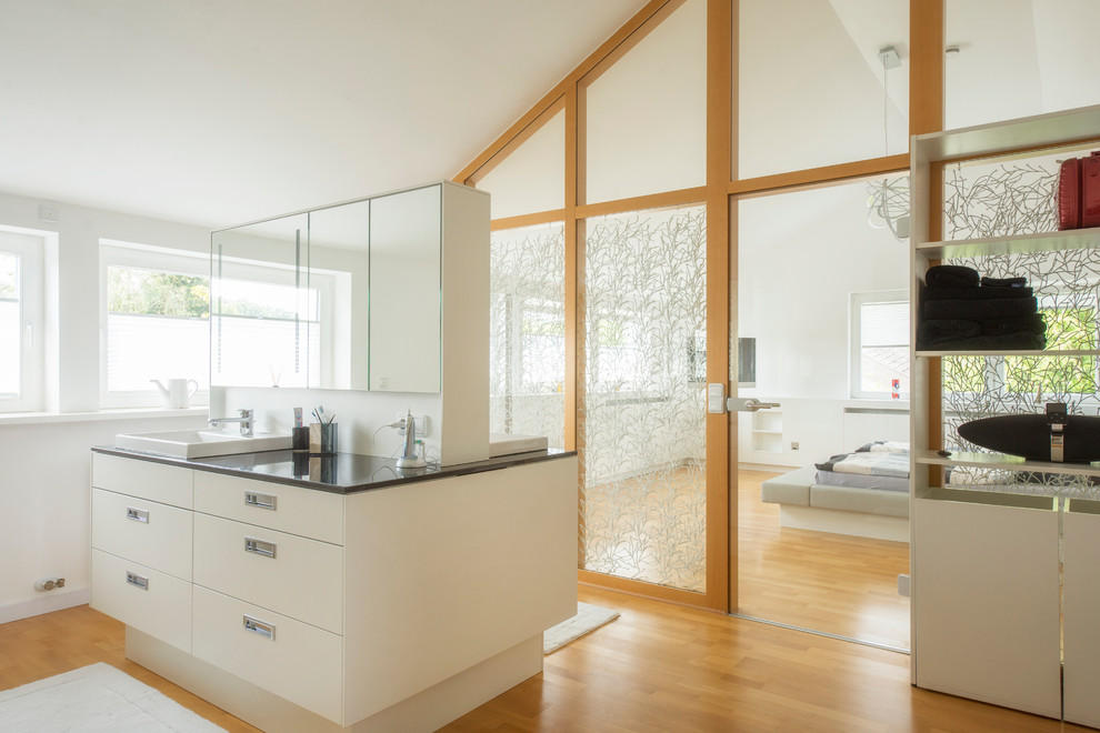 Inspiration for a large contemporary master bathroom in Nuremberg with flat-panel cabinets, white cabinets, white walls, medium hardwood floors and a drop-in sink.