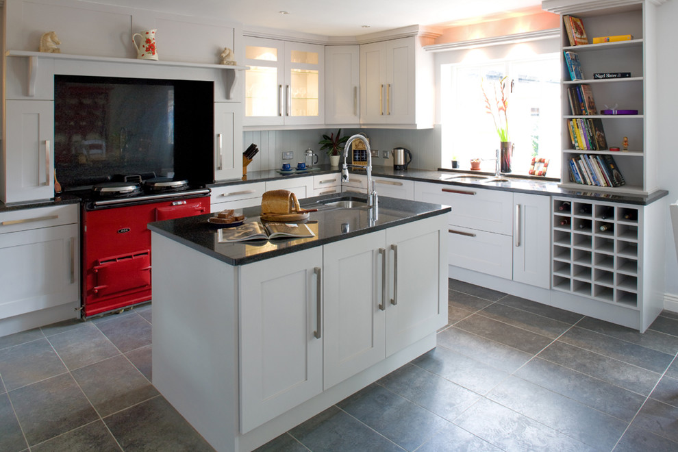 This is an example of a transitional kitchen in Other with coloured appliances, shaker cabinets, white cabinets, black splashback and stone slab splashback.