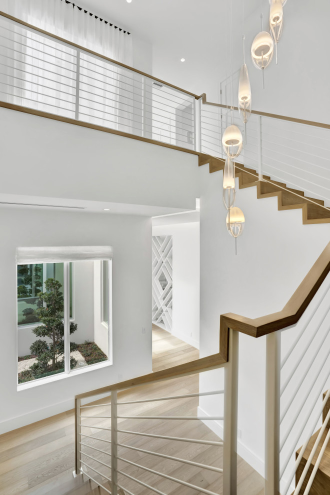 Inspiration for a large contemporary wood u-shaped staircase in Miami with wood risers and metal railing.