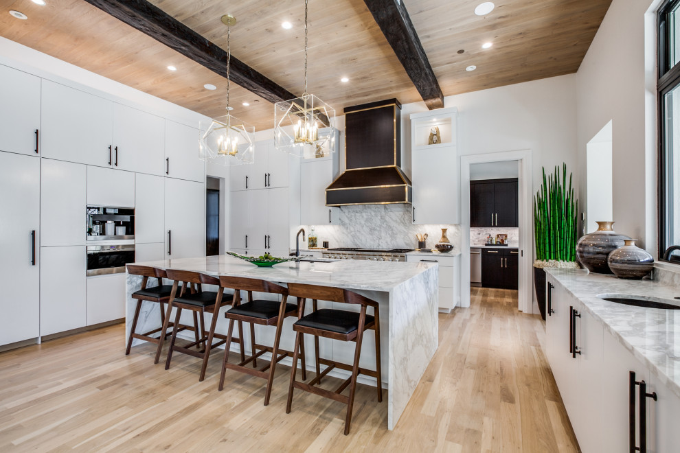 Photo of a large mediterranean eat-in kitchen in Dallas with a drop-in sink, flat-panel cabinets, white cabinets, marble benchtops, stainless steel appliances, with island, multi-coloured benchtop and exposed beam.
