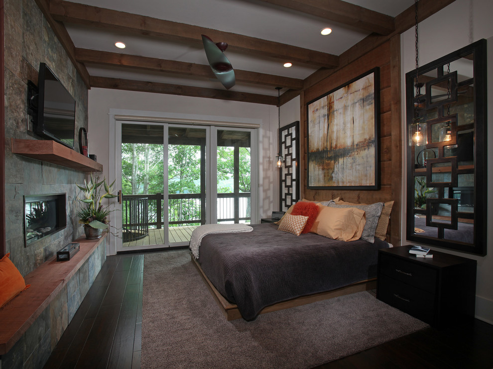 This is an example of a mid-sized country master bedroom in Atlanta with beige walls, dark hardwood floors, a ribbon fireplace and a stone fireplace surround.