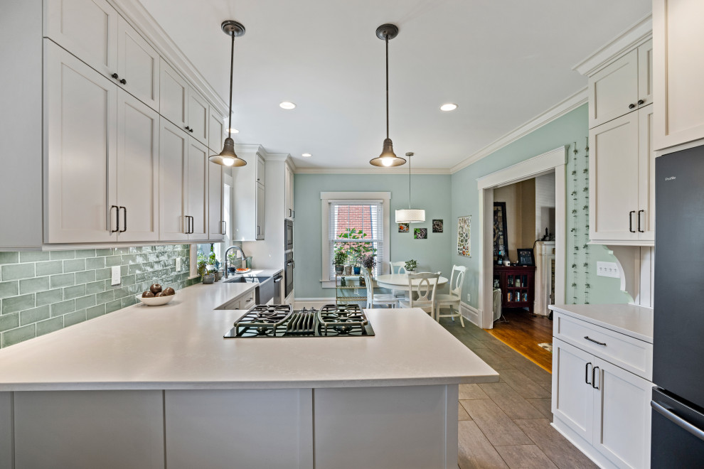 Bild på ett mellanstort vintage vit vitt kök, med en rustik diskho, skåp i shakerstil, vita skåp, bänkskiva i kvarts, grönt stänkskydd, stänkskydd i cementkakel, svarta vitvaror, klinkergolv i porslin, en halv köksö och grått golv