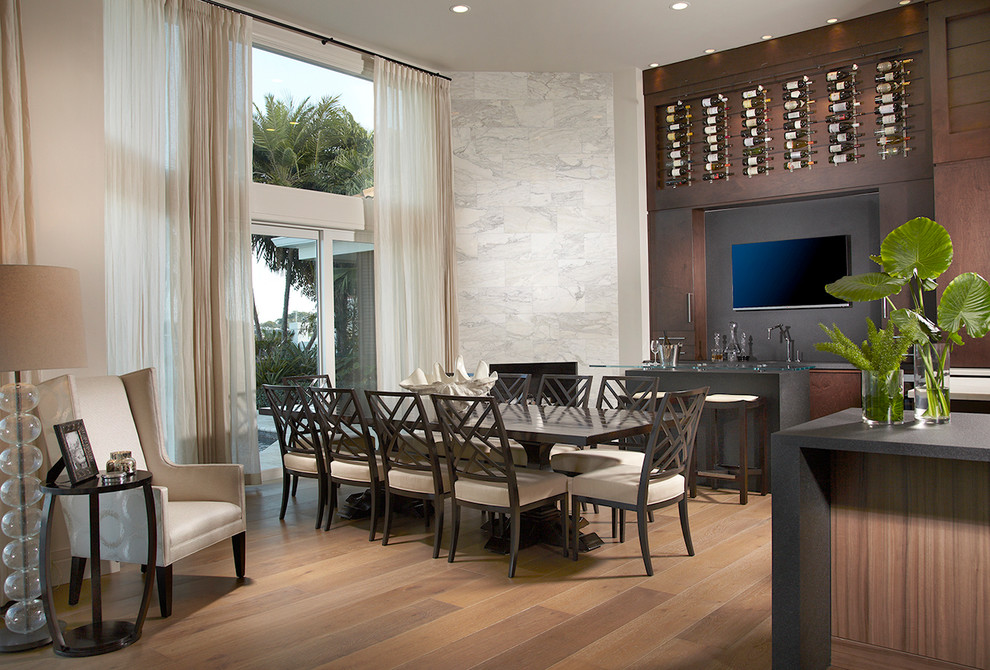 This is an example of an expansive tropical open plan dining in Miami with white walls, porcelain floors, beige floor, a corner fireplace and a stone fireplace surround.