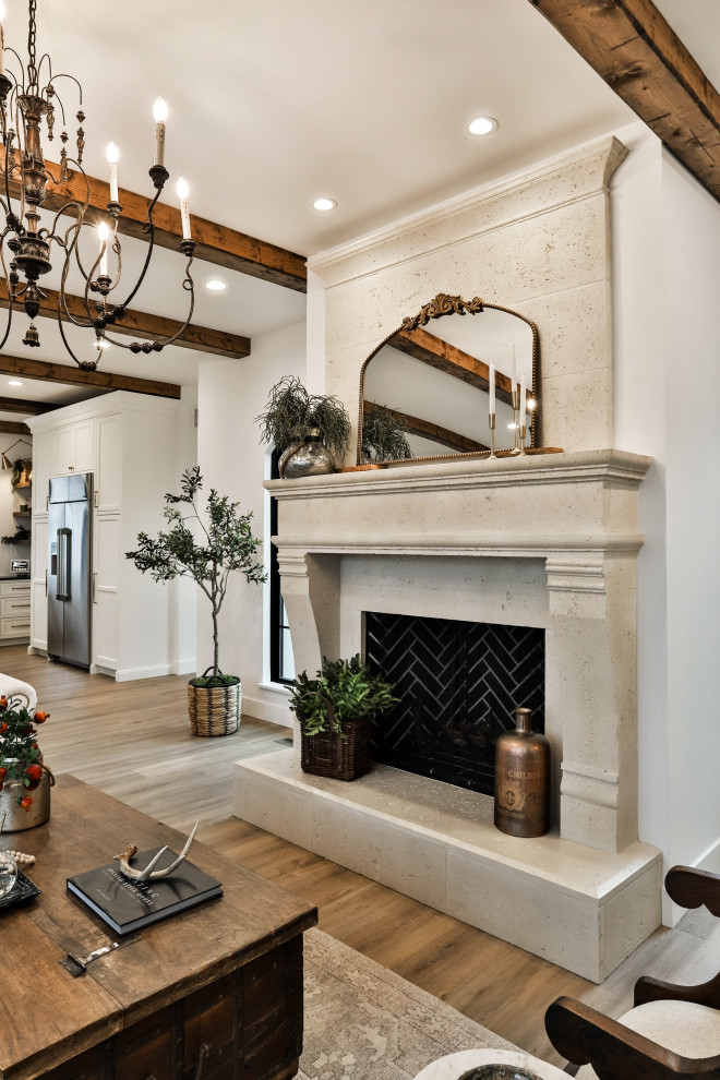 Example of a mid-sized tuscan formal and open concept medium tone wood floor, beige floor and exposed beam living room design in Other with white walls, a standard fireplace, a stone fireplace and no tv