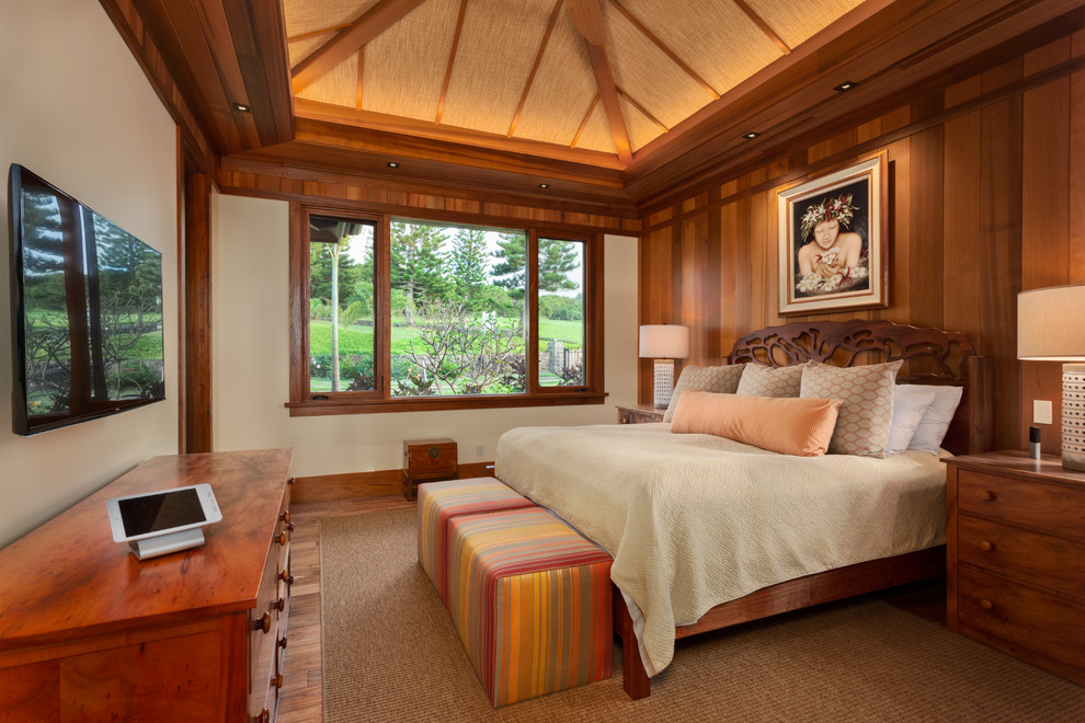 Photo of a mid-sized tropical guest bedroom in Hawaii with beige walls, medium hardwood floors and brown floor.