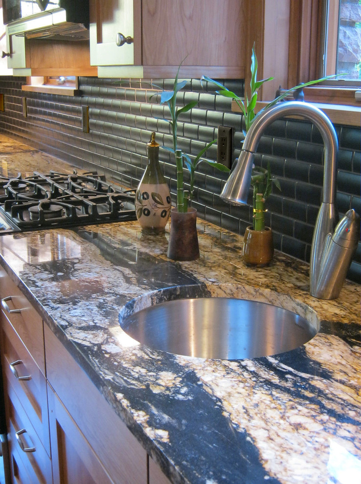 Kitchen - transitional l-shaped medium tone wood floor kitchen idea in Denver with a single-bowl sink, shaker cabinets, medium tone wood cabinets, granite countertops, black backsplash, ceramic backsplash, stainless steel appliances and an island