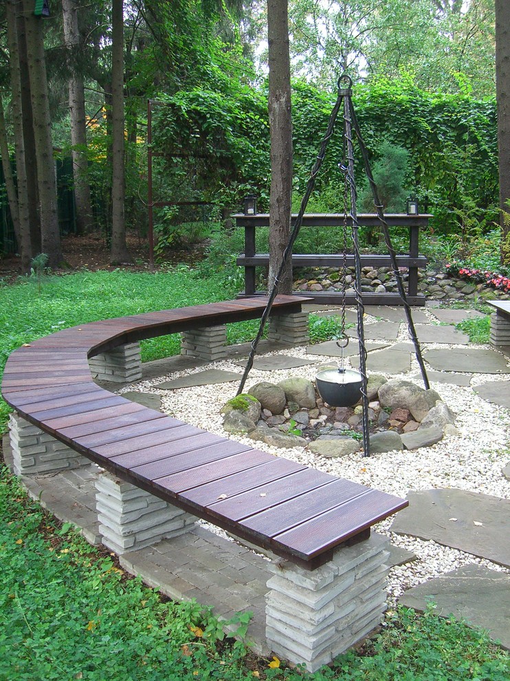 This is an example of a contemporary partial sun garden for summer in Moscow with a fire feature and natural stone pavers.