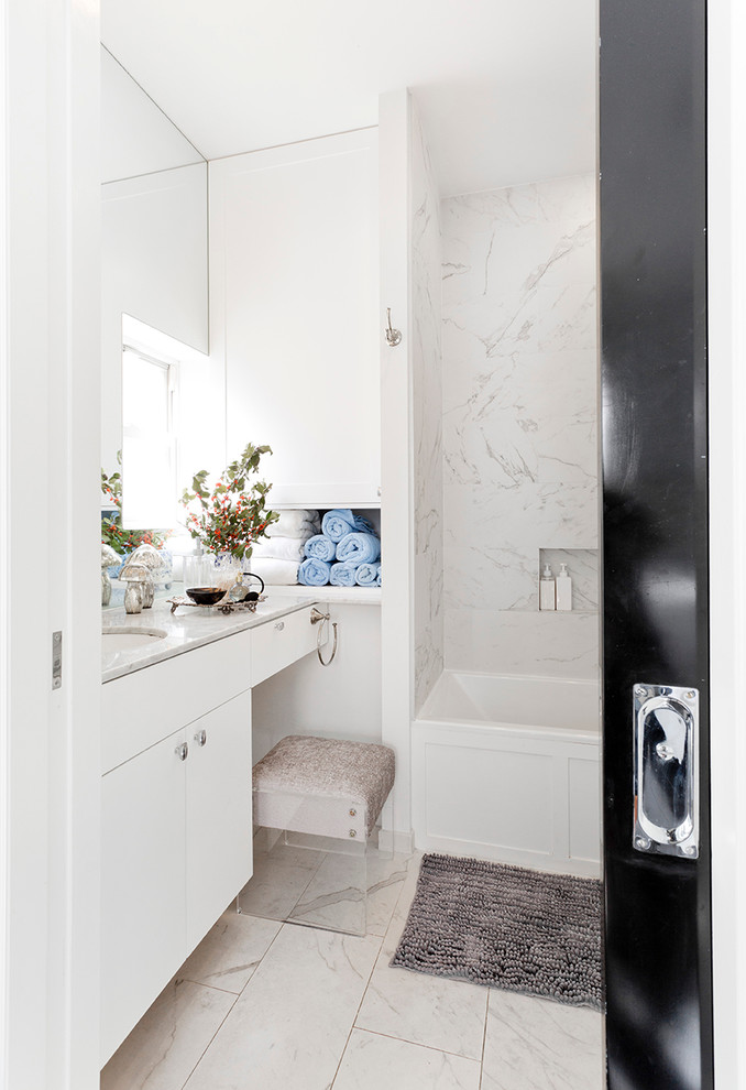 This is an example of a small transitional master bathroom in New York with shaker cabinets, white cabinets, an alcove tub, an alcove shower, a two-piece toilet, white tile, porcelain tile, white walls, porcelain floors, an undermount sink and marble benchtops.