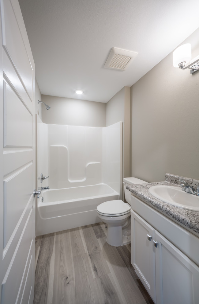 На фото: детская ванная комната среднего размера в классическом стиле с фасадами с утопленной филенкой, белыми фасадами, ванной в нише, душем над ванной, унитазом-моноблоком, белой плиткой, стеклянной плиткой, бежевыми стенами, полом из ламината, накладной раковиной, столешницей из ламината, серым полом, шторкой для ванной, разноцветной столешницей, тумбой под одну раковину и встроенной тумбой