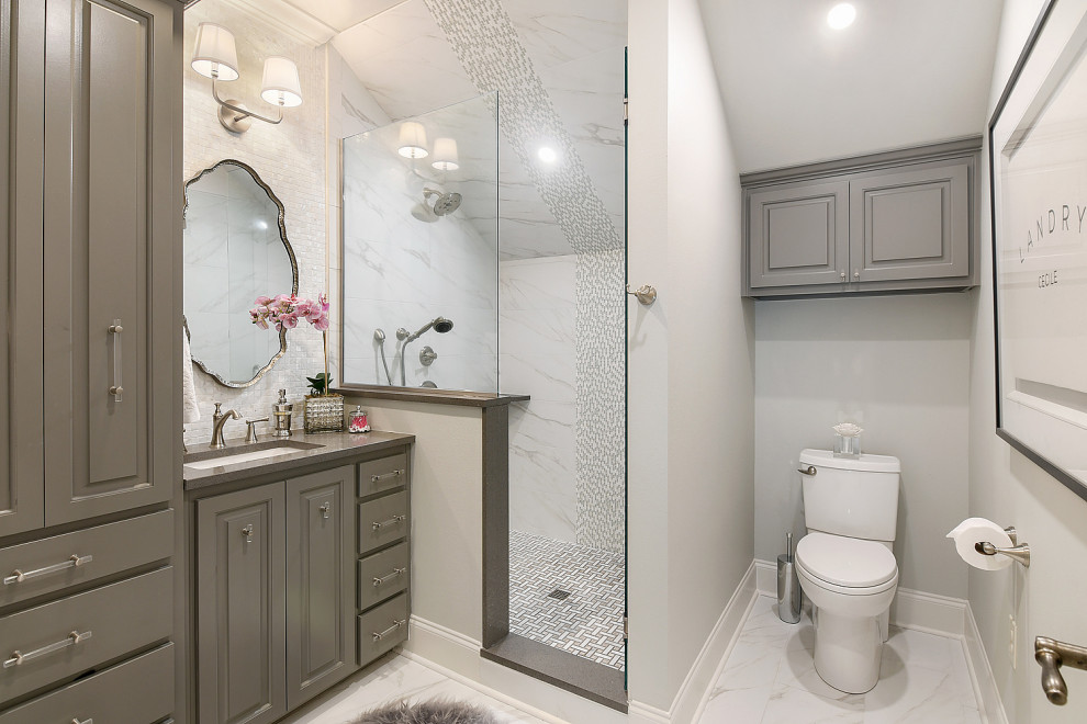 Inspiration for a mid-sized transitional 3/4 white tile and marble tile ceramic tile, white floor, single-sink and wallpaper corner shower remodel with gray cabinets, a one-piece toilet, white walls, an undermount sink, quartzite countertops, a hinged shower door, gray countertops, a built-in vanity and raised-panel cabinets