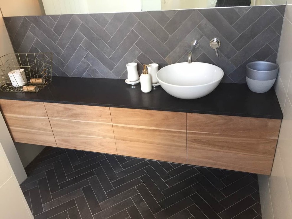 This is an example of a mid-sized beach style 3/4 bathroom in Sydney with flat-panel cabinets, medium wood cabinets, gray tile, stone tile and granite benchtops.