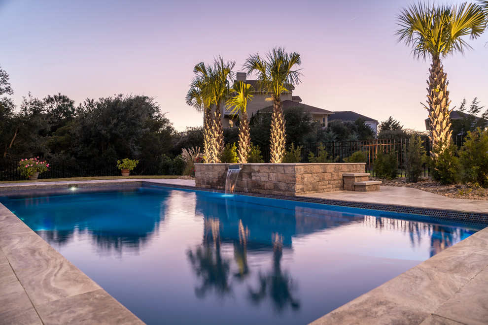 Large beach style backyard rectangular pool in Other with a hot tub and natural stone pavers.