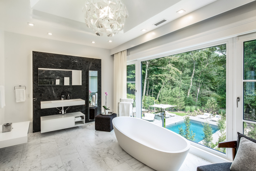 This is an example of a contemporary bathroom in New York with flat-panel cabinets, white cabinets, a freestanding tub, black tile, white walls, an integrated sink, multi-coloured floor, white benchtops, a single vanity, a floating vanity and recessed.