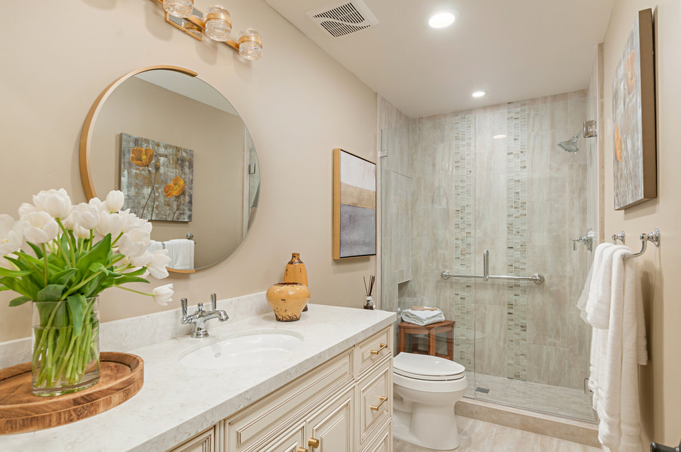 Photo of a mid-sized traditional 3/4 bathroom in San Diego with raised-panel cabinets, beige cabinets, an alcove shower, a two-piece toilet, beige tile, porcelain tile, beige walls, porcelain floors, an undermount sink, engineered quartz benchtops, beige floor, a hinged shower door and white benchtops.