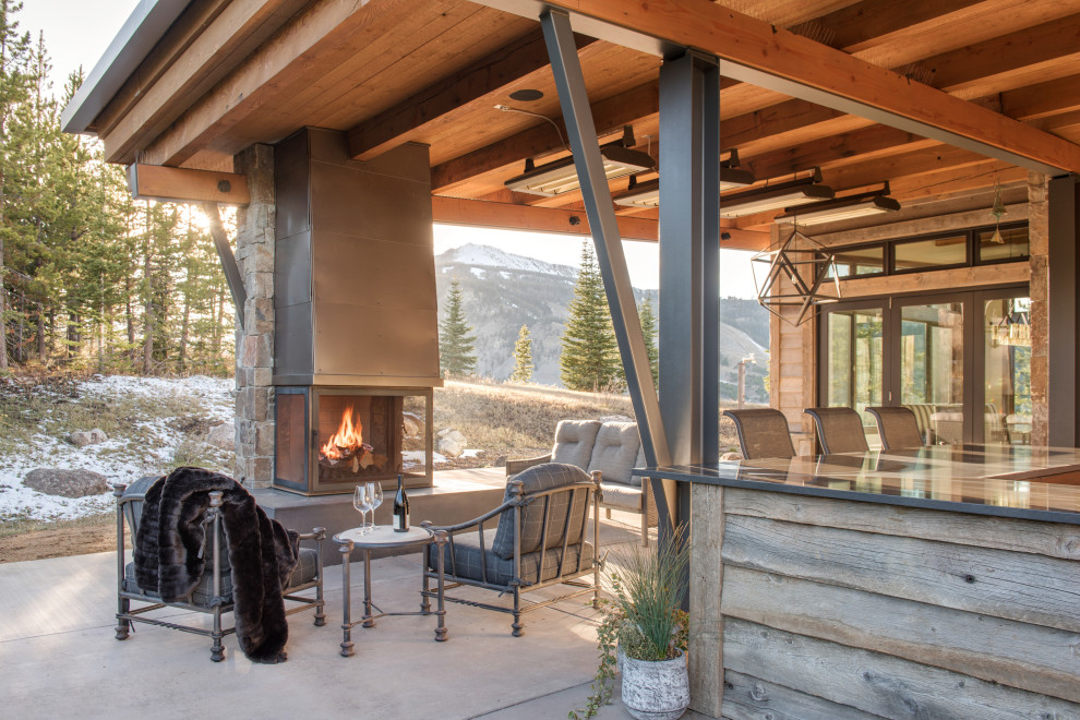Patio - rustic concrete patio idea with a fireplace and a roof extension