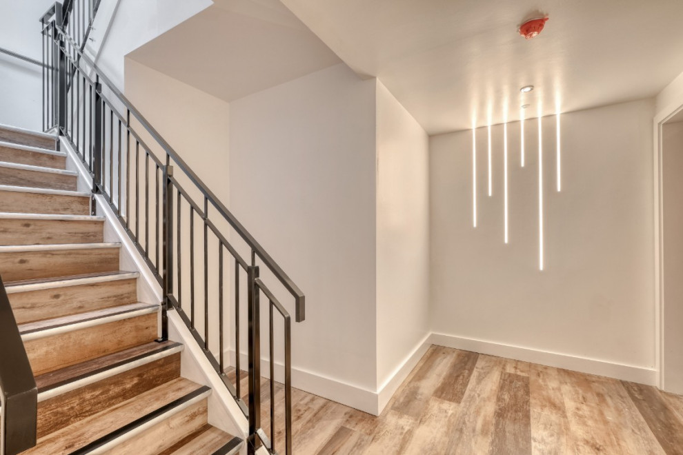 Photo of an expansive scandinavian u-shaped metal railing staircase in Other with wood risers and feature lighting.
