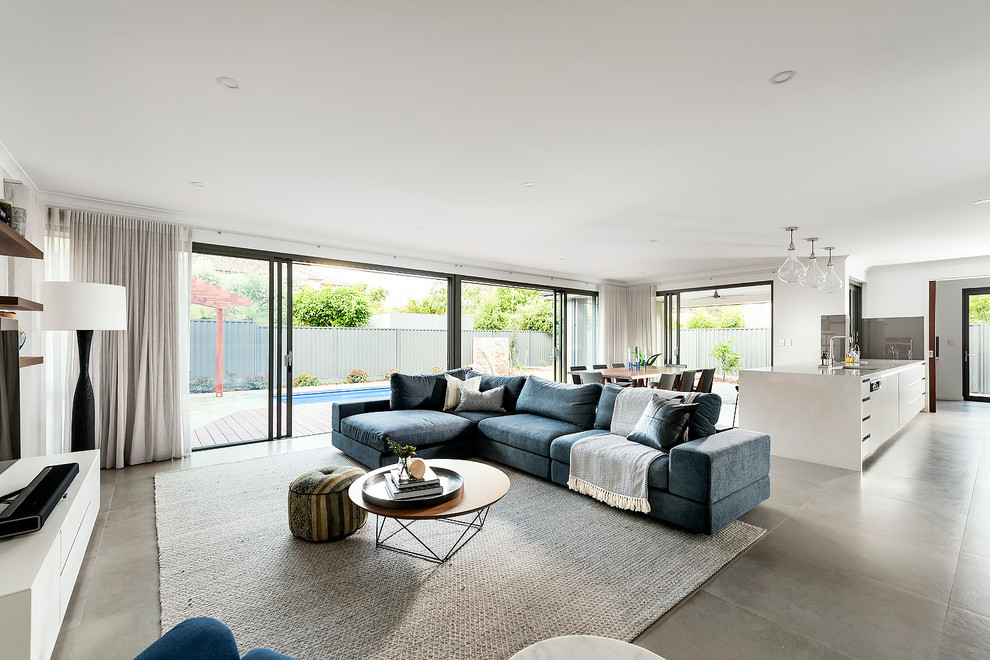 Large modern open concept living room in Perth with white walls, porcelain floors and a freestanding tv.