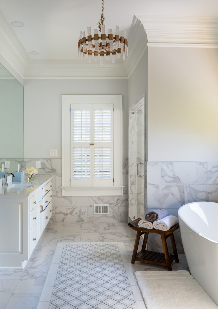 Inspiration for a large transitional master white tile and marble tile ceramic tile, white floor and double-sink freestanding bathtub remodel in Atlanta with raised-panel cabinets, white cabinets, a two-piece toilet, gray walls, an undermount sink, quartz countertops, a hinged shower door, white countertops and a built-in vanity