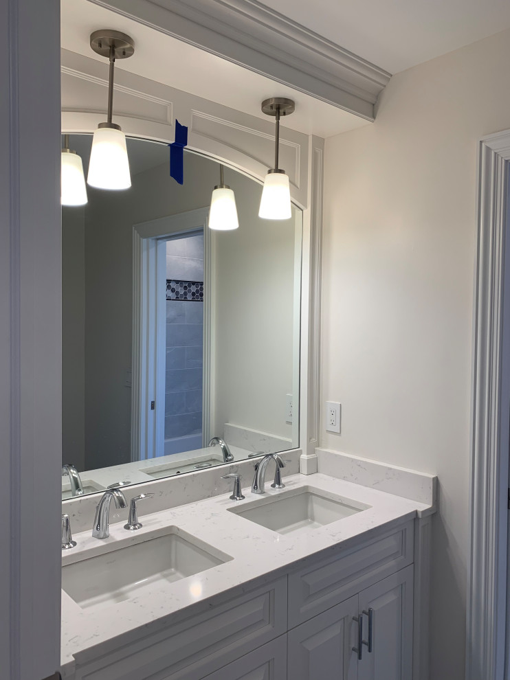 This is an example of a mid-sized traditional bathroom in New York with shaker cabinets, white cabinets, a one-piece toilet, grey walls, a pedestal sink, grey floor and a hinged shower door.